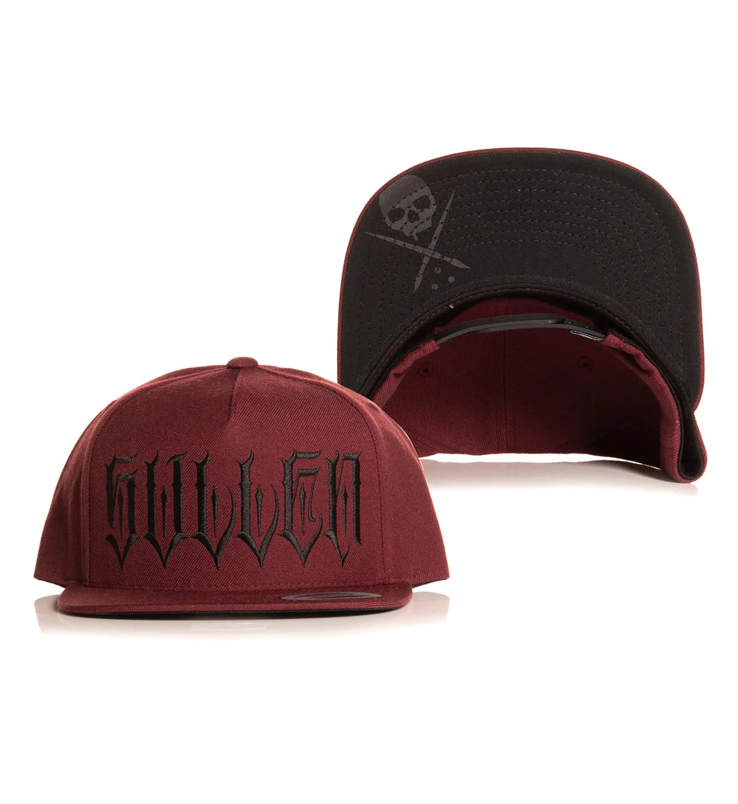 red snapback with sullen badge and tattoo font